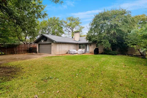a front view of house with yard and trees in the background