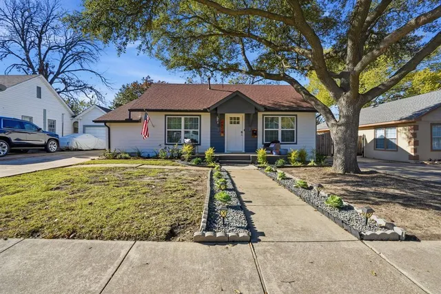 a view of a white house next to a yard with plants and trees