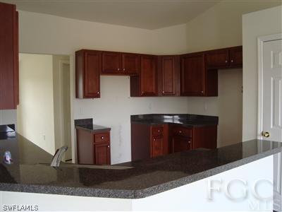 8141 Liriope Loop Lehigh Acres, FL 33972 - Photo 3 of 6 a kitchen with stainless steel appliances granite countertop a refrigerator and a stove top oven
