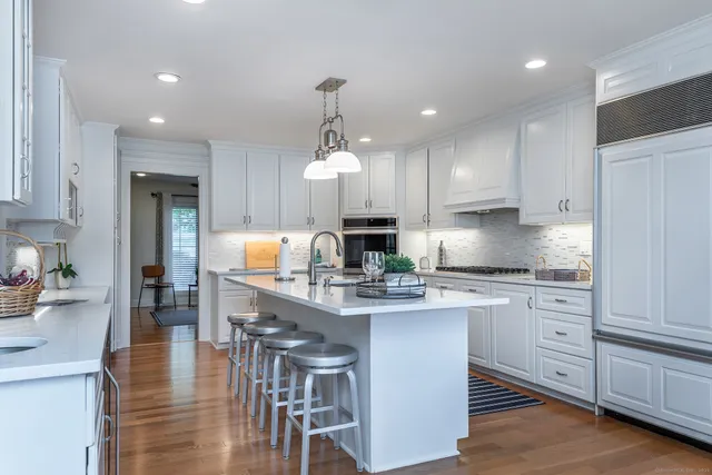 a large kitchen with kitchen island granite countertop lots of white cabinets appliances and furniture