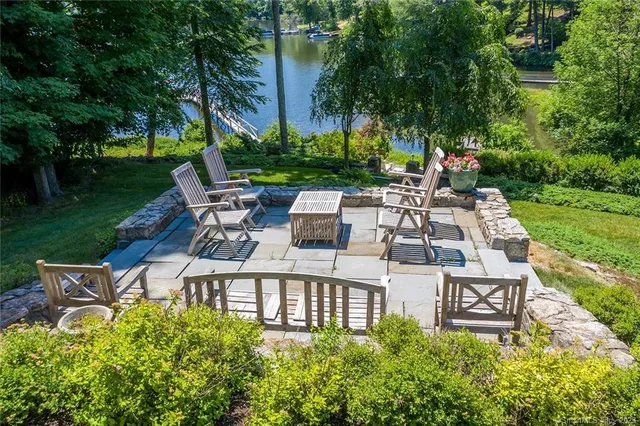 a view of a patio with table and chairs and potted plants and large trees