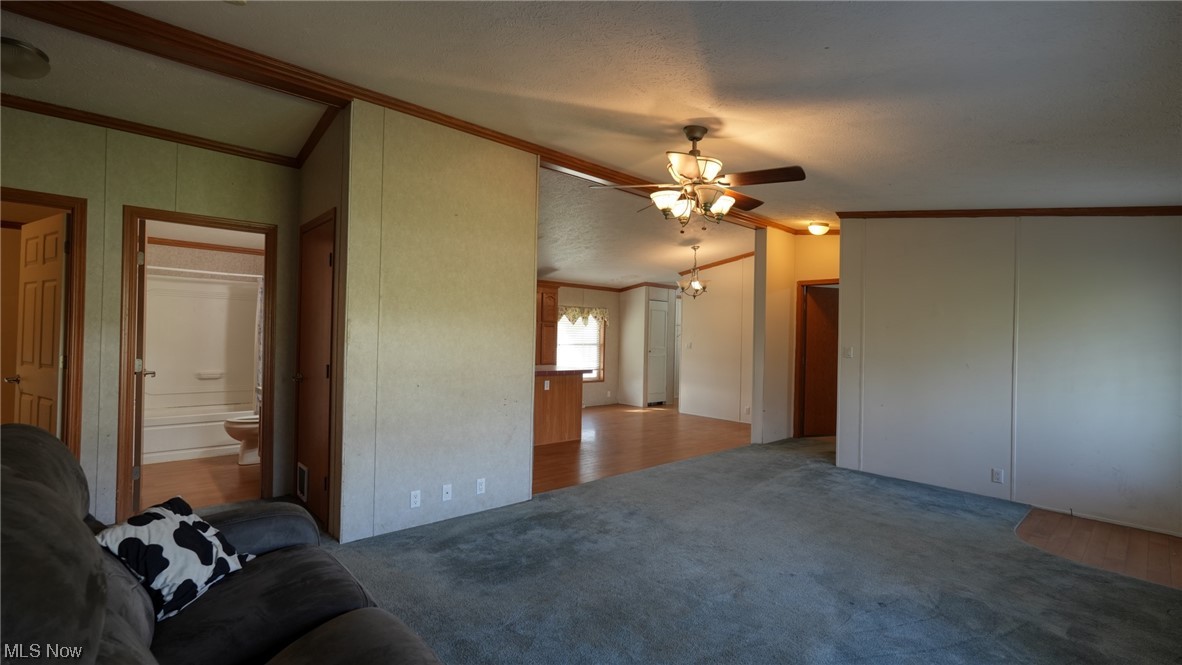 59062 Marietta Road Byesville, OH 43723 - Photo 4 of 33 Unfurnished living room featuring light carpet, crown molding, lofted ceiling, and ceiling fan