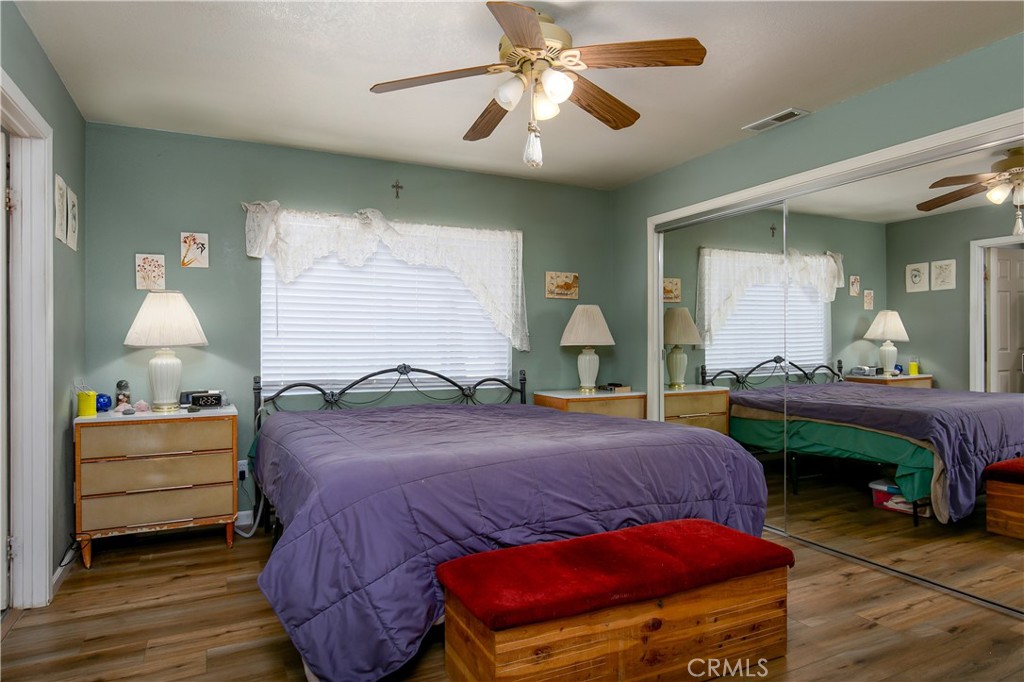 10960 Steinhoff Road Frazier Park, CA 93225 - Photo 31 of 46 The generous primary bedroom suite provides a relaxing retreat. The space highlights continuous wood-look flooring, soft sage-green walls, and expansive floor-to-ceiling mirrored closet doors that amplify the natural light filtering through the large window.