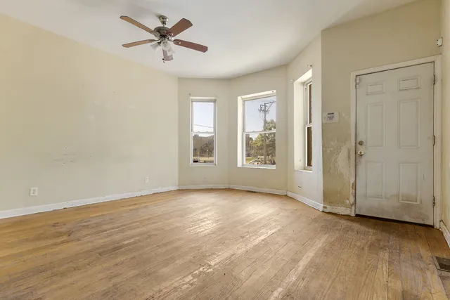 an empty room with fan and windows