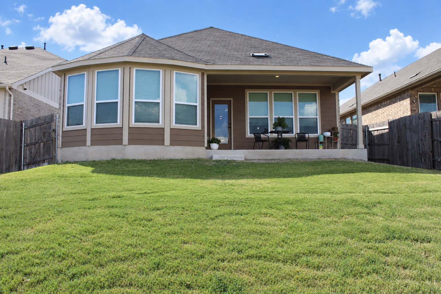 181 Tree Nut Loop Buda, TX 78610 - Photo 24 of 33 A spacious grassy lawn slopes gently toward the covered back porch and bay window extension.