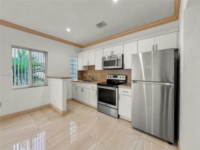 a kitchen with white cabinets stainless steel appliances and window