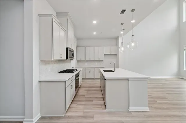 a kitchen with stainless steel appliances granite countertop a sink a stove and a refrigerator