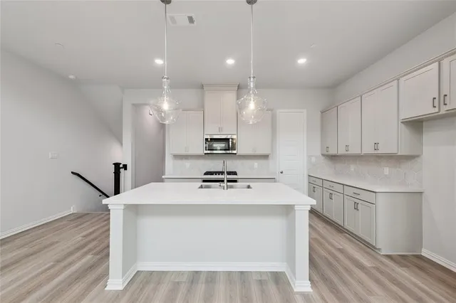 a kitchen with a sink a stove a refrigerator and white cabinets