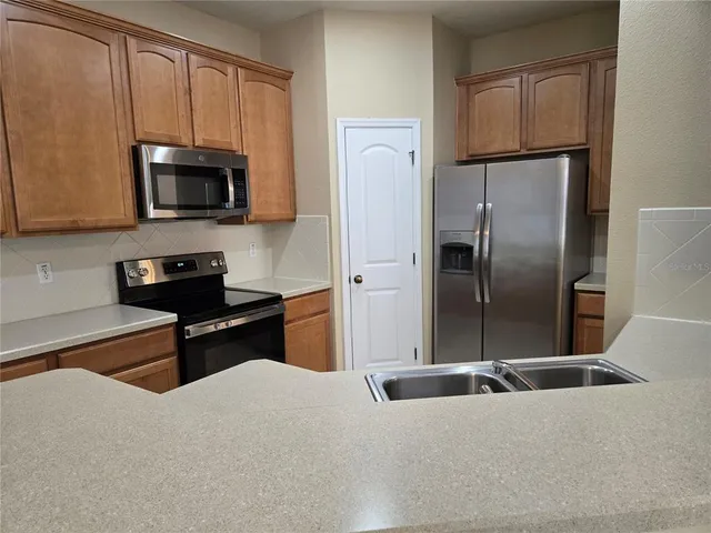 a kitchen with stainless steel appliances granite countertop a refrigerator a stove a microwave and sink