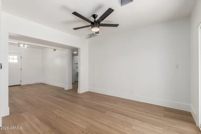 an empty room with wooden floor and a ceiling fan