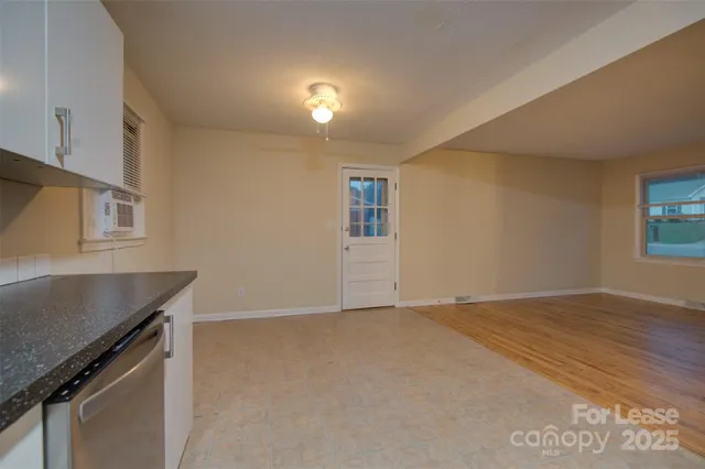 a view of an empty room with window and wooden floor