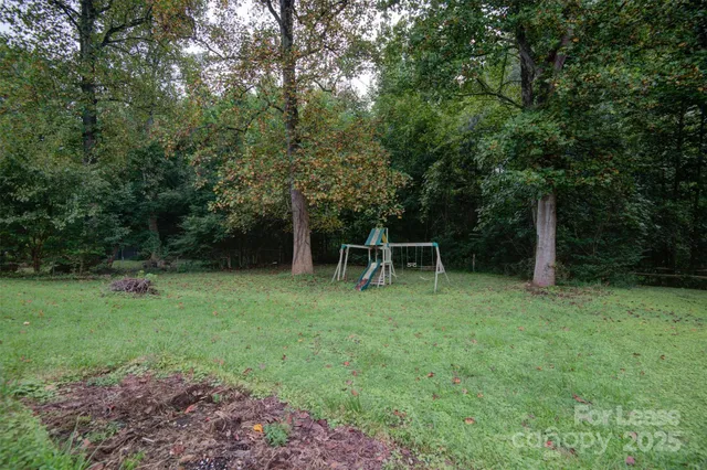 a backyard of a house with plants and large trees