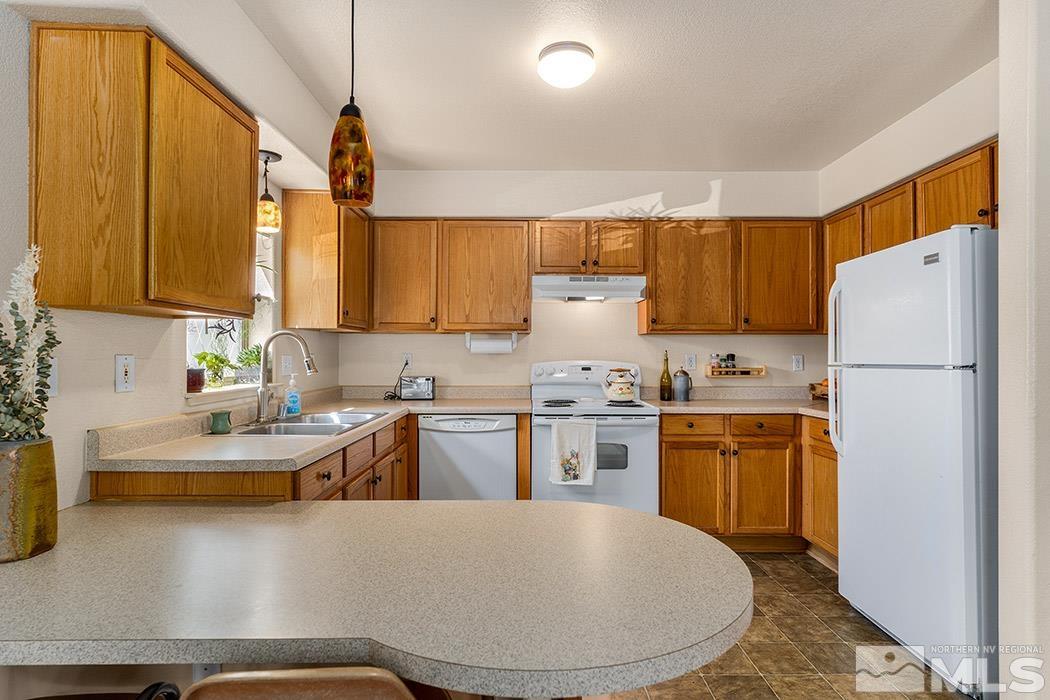 617 Elko Avenue Reno, NV 89512 - Photo 6 of 14 a kitchen with stainless steel appliances granite countertop a refrigerator a sink dishwasher a stove with wooden cabinets and floor