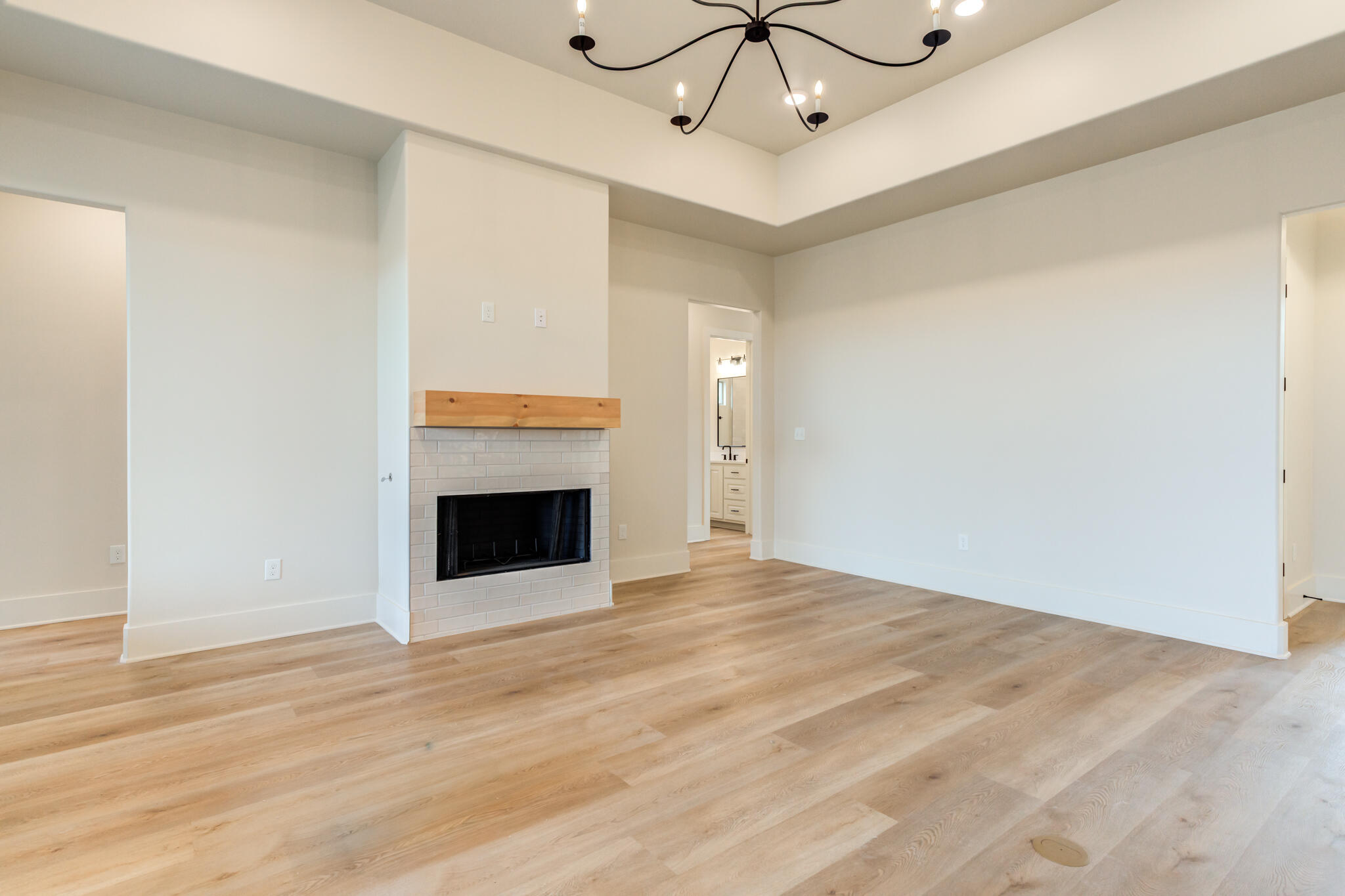 3516 141st Street Lubbock, TX 79423 - Photo 20 of 56 a view of an empty room with a chandelier fan and a fireplace