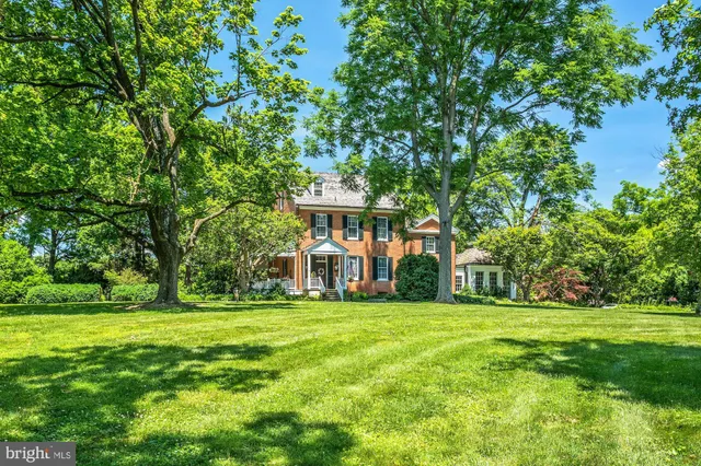 a view of a white house with a big yard and large trees