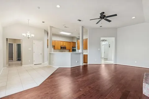 a view of a big room with wooden floor and a kitchen