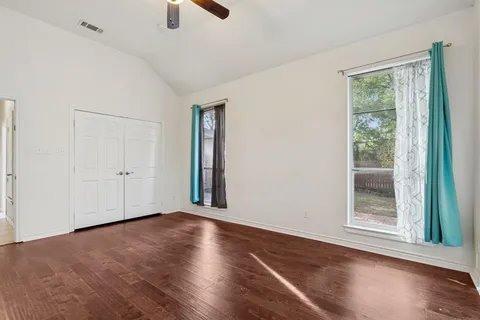 an empty room with wooden floor cabinet and windows