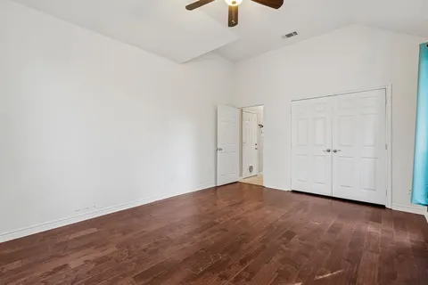 an empty room with wooden floor cabinet and windows
