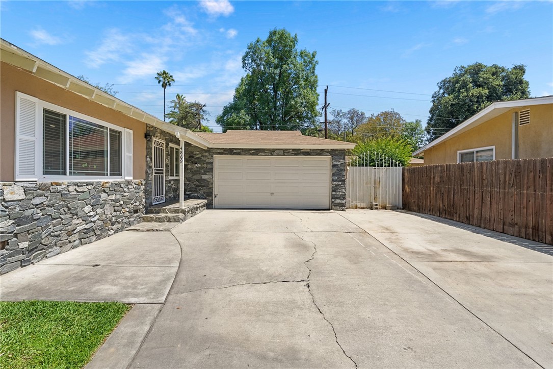 4869 Serrano Place Riverside, CA 92504 - Photo 11 of 40 Welcoming exterior featuring a wide driveway with generous parking space, attached two-car garage, and mature surrounding landscaping.