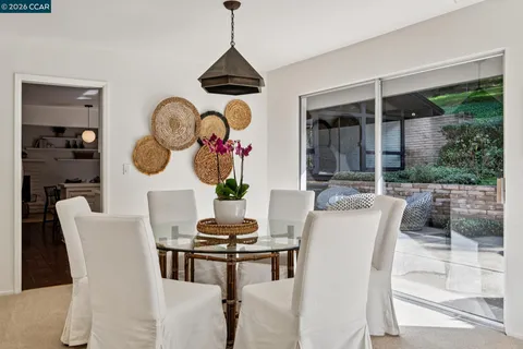 a dining room with furniture a rug a potted plant and a wooden floor