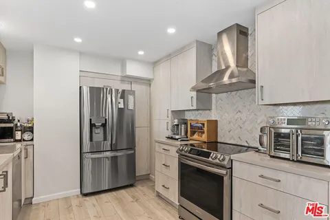 a kitchen with stainless steel appliances kitchen island granite countertop a refrigerator stove and sink