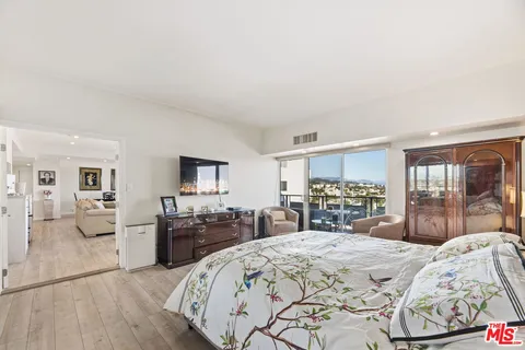 a large bedroom with a bed and wooden floor