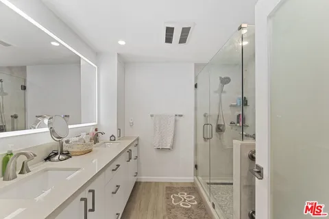 a bathroom with a double vanity sink mirror and shower