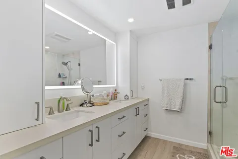 a bathroom with a double vanity sink mirror and shower