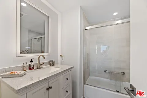 a bathroom with a granite countertop sink mirror and a bathtub