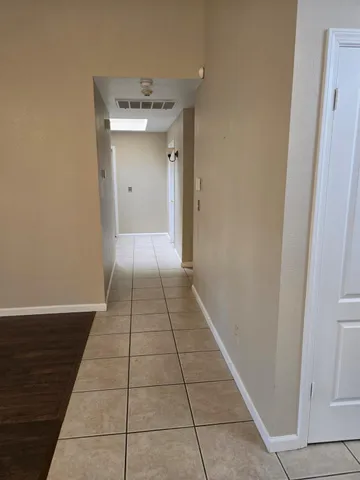a view of a hallway with wooden floor and a bathroom