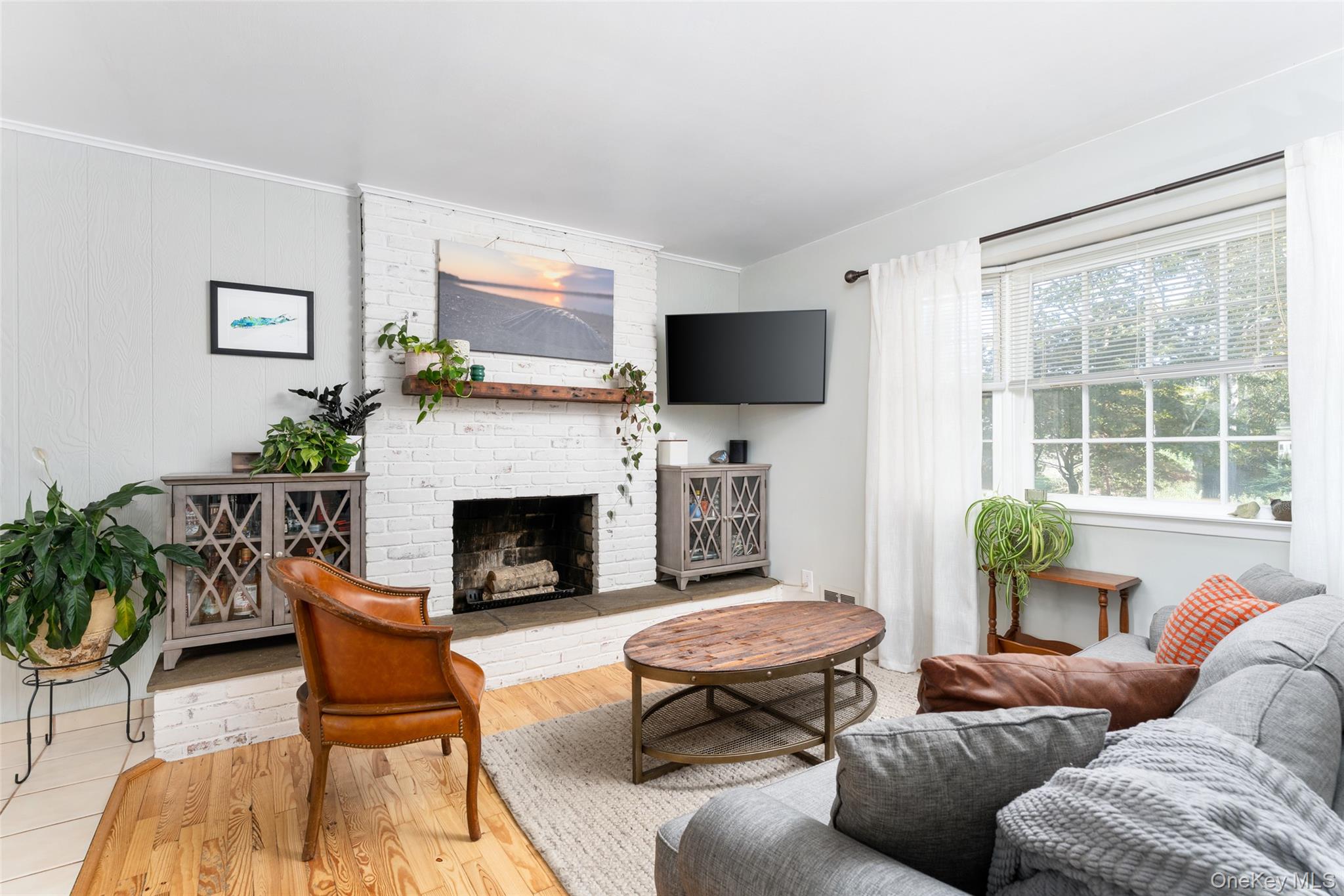8 Foxboro Road Hampton Bays, NY 11946 - Photo 12 of 50 a living room with furniture a flat screen tv and a fireplace