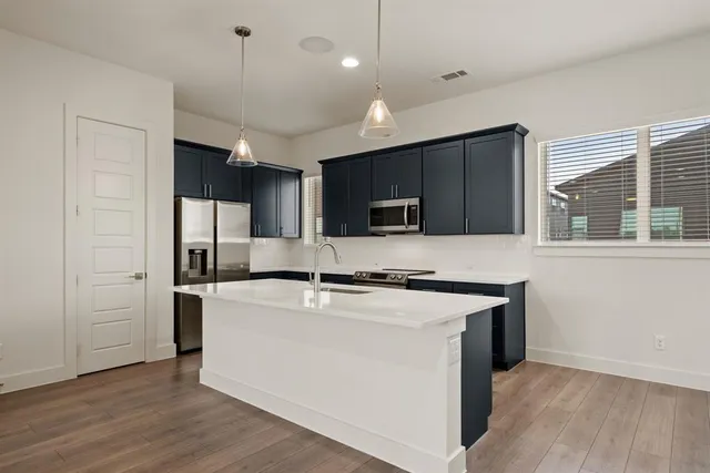 a kitchen with stainless steel appliances granite countertop a sink a stove a refrigerator and island with wooden floor