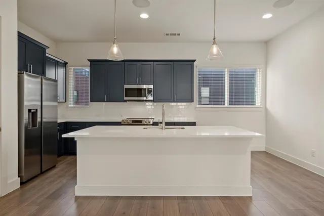 a kitchen with kitchen island stainless steel appliances a sink and a refrigerator