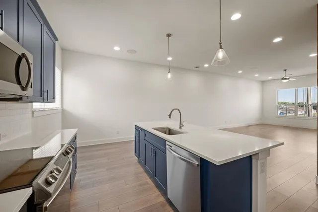 a kitchen with a sink and a stove top oven with wooden floor