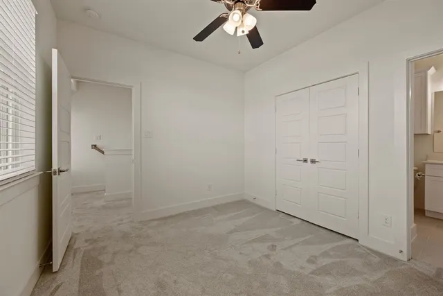 an empty room with a chandelier fan and closet area
