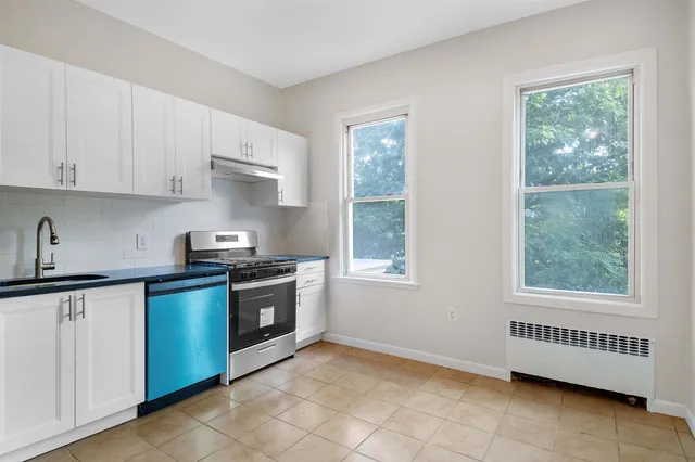 a kitchen with stainless steel appliances granite countertop a stove a sink and white cabinets