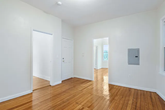 an empty room with wooden floor and bathroom
