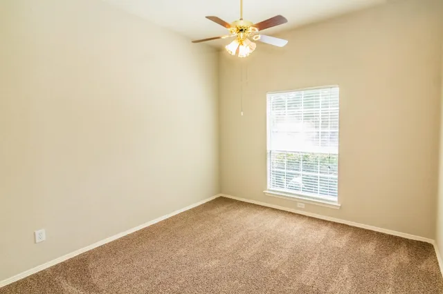 an empty room with a window and a fan