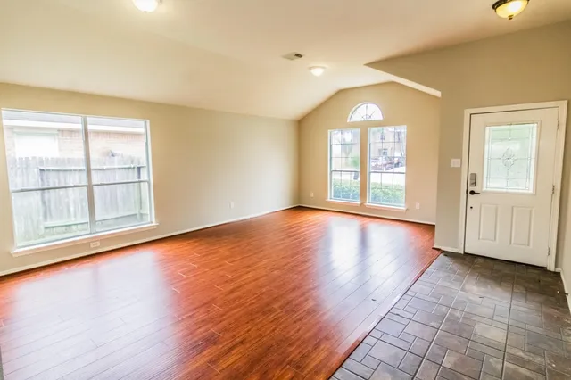 an empty room with wooden floor and windows