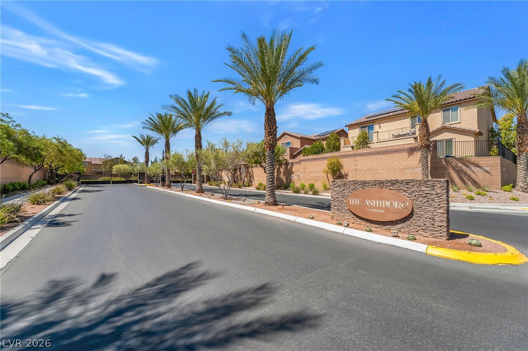 6245 Andover Wood Road Las Vegas, NV 89113 - Photo 37 of 37 Secure community entry with a stone-clad sign, lined by graceful palm trees and desert landscaping.