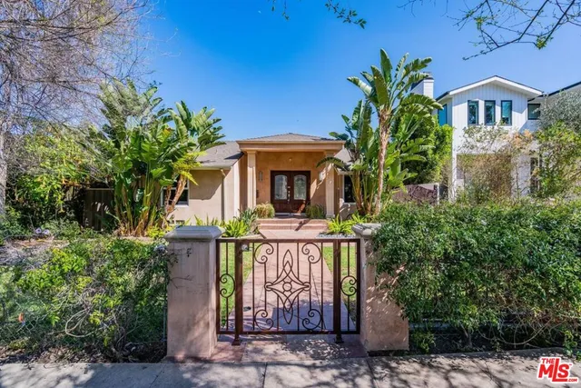 a view of a brick house with plants and large tree