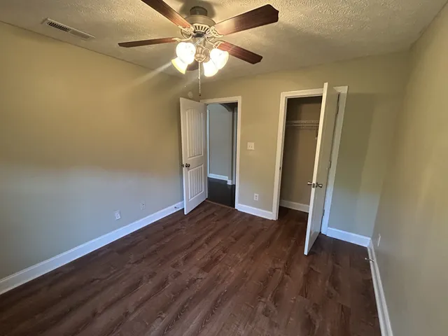 an empty room with wooden floor closet and ceiling fan