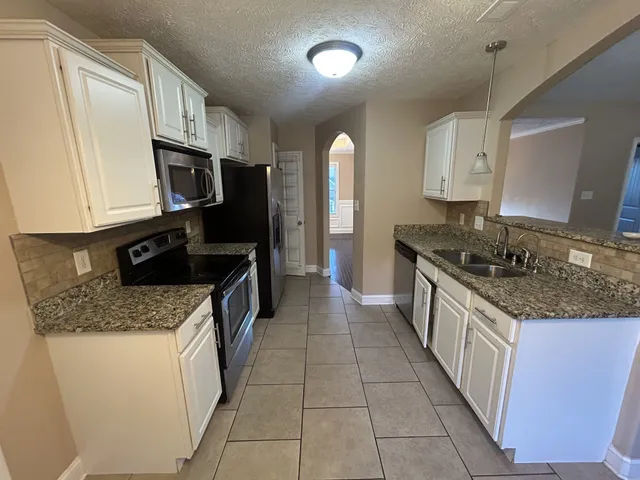 a kitchen with stainless steel appliances granite countertop a sink stove and cabinets