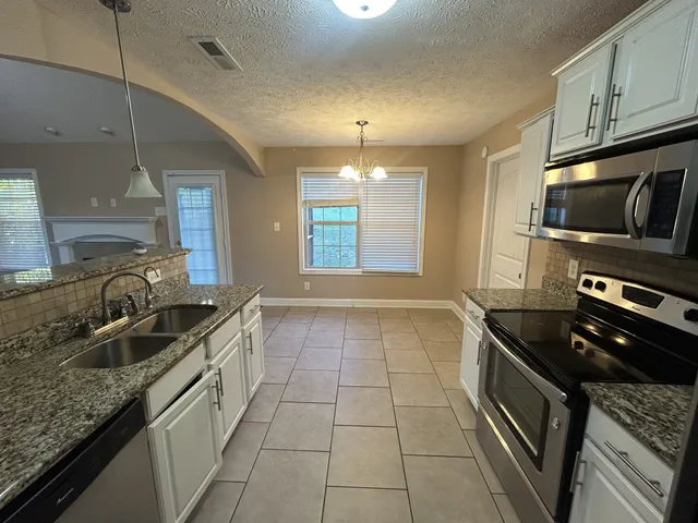 a kitchen with granite countertop a sink a counter top space appliances and cabinets