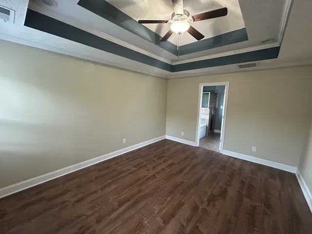 a view of an empty room with wooden floor and a ceiling fan