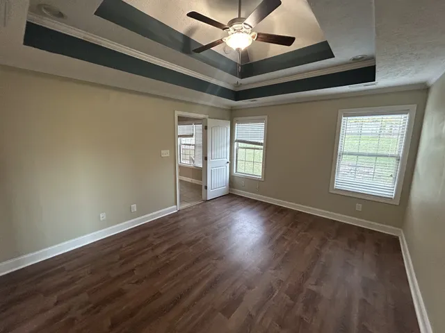 a view of an empty room with a window and wooden floor