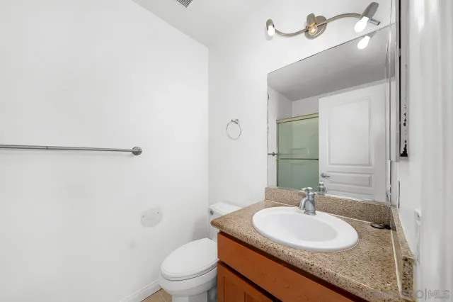 a bathroom with a granite countertop sink toilet a mirror and shower
