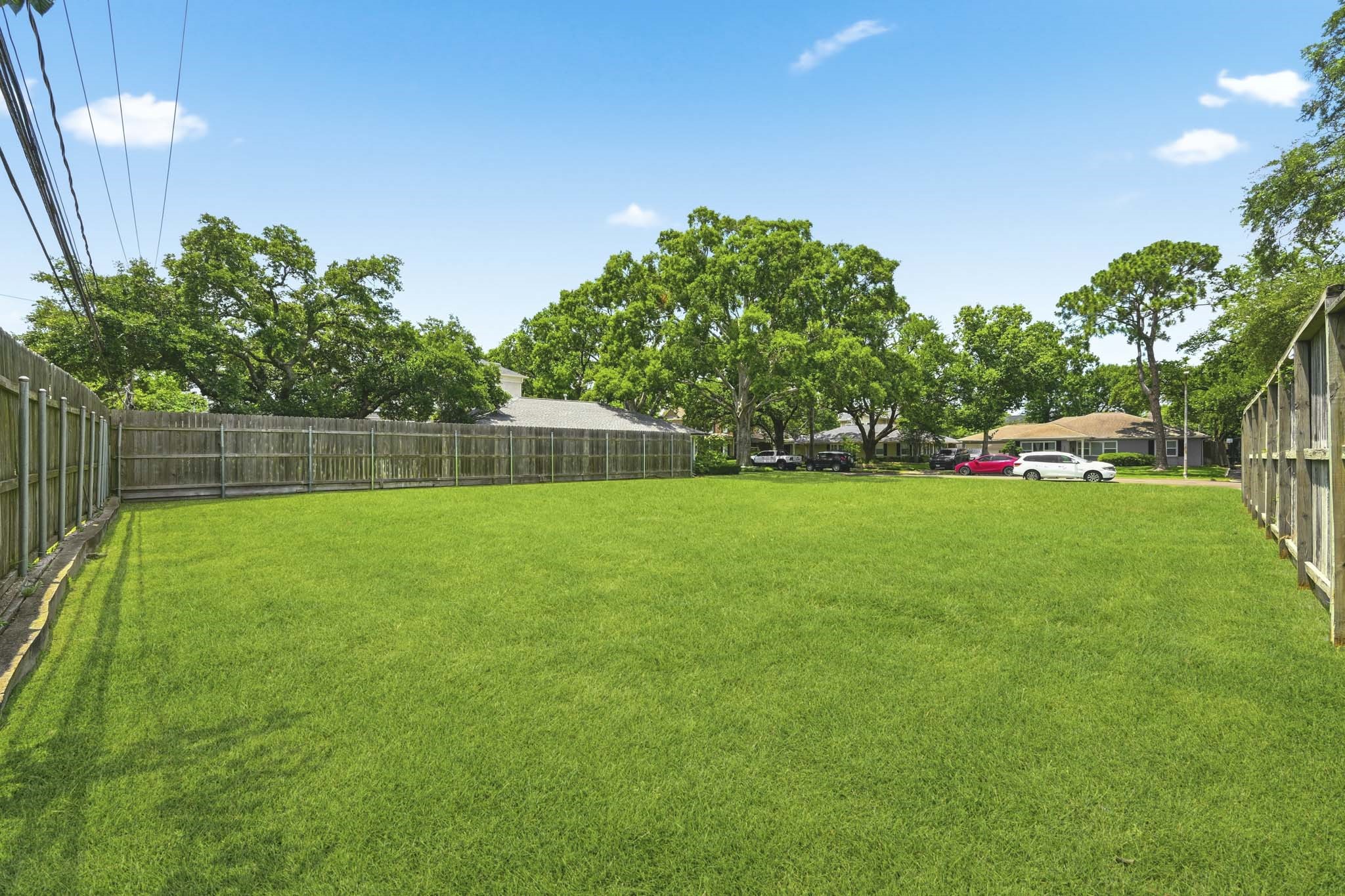 4227 Markham Street Houston, TX 77027 - Photo 4 of 7 Spacious, fenced-in grassy yard with mature trees in a residential neighborhood, perfect for outdoor activities and privacy.