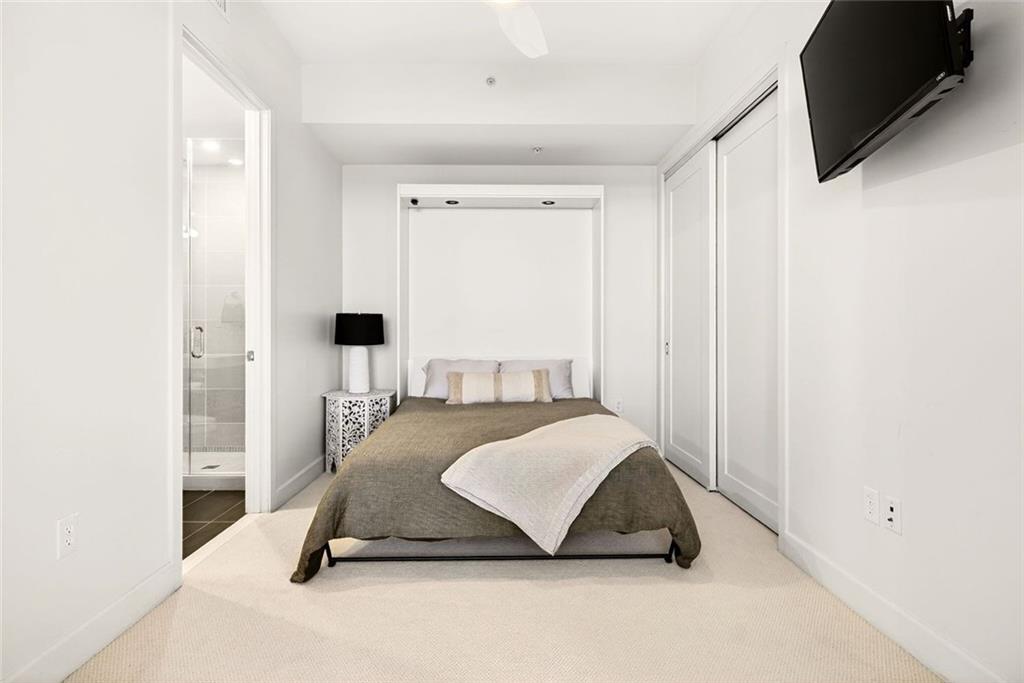 1820 Peachtree Road Northwest, Unit 905 Atlanta, GA 30309 - Photo 12 of 41 a living room with a bed furniture and a flat screen tv