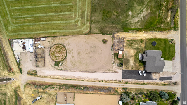 5702 950 North Ogden, UT 84404 - Photo 11 of 36 Expansive property featuring a large residence with a dark gray roof, a circular dirt arena, multiple outbuildings, a paved driveway, and substantial undeveloped land
